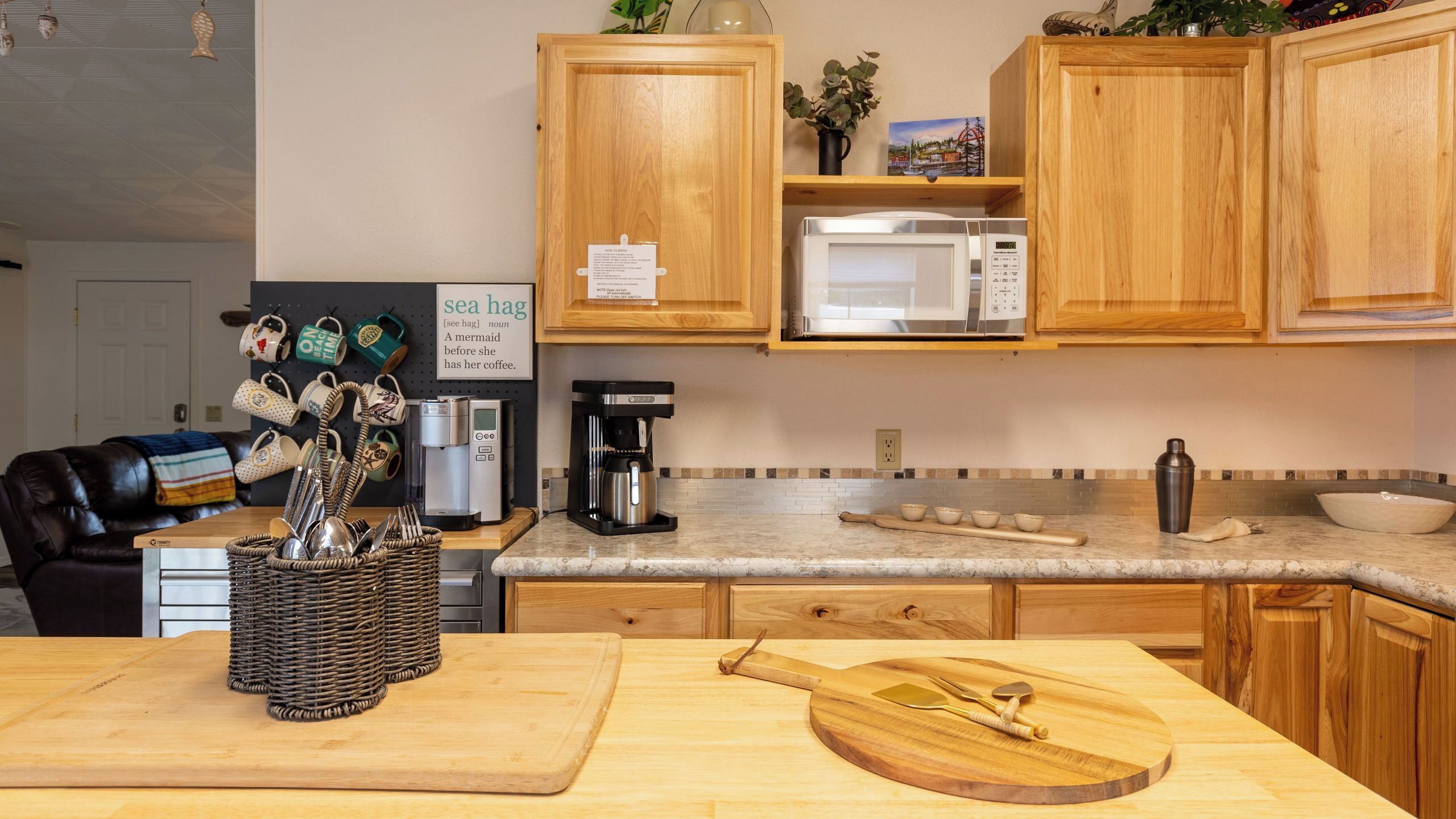 A kitchen with wooden cabinets, a microwave, coffee maker, and various kitchen utensils.
