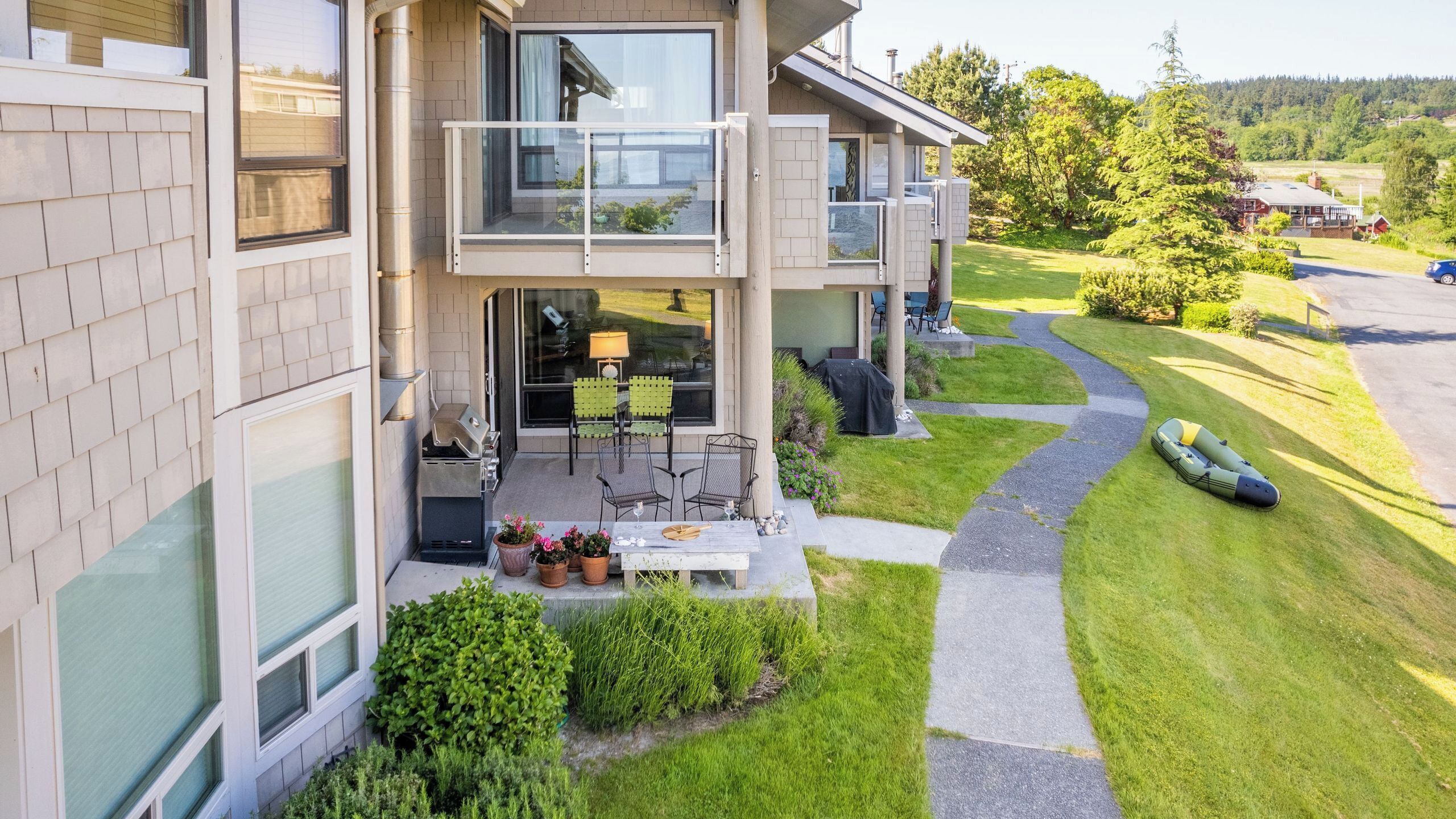 A modern two-story house with a patio, outdoor seating, and a well-maintained lawn.
