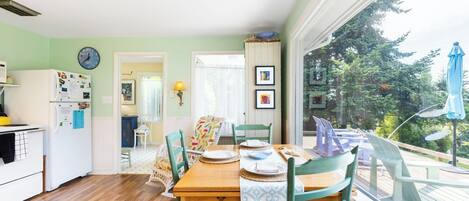 A dining area with a wooden table, chairs, and a view of the outdoors.