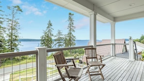 A wooden deck with two chairs and a table, overlooking a body of water and trees. - The Lookout at Crane's Landing by Avantstay (Greenbank)