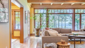 Un amplio salón con ventanas grandes, techo de madera y una zona de estar acogedora.