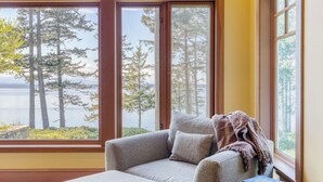 Una habitación con un ventanal que ofrece vistas a un bosque y una masa de agua.