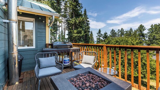 A deck with a fire pit, outdoor seating, and a grill.