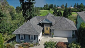 A residential house with a garage, a front yard, and a view of a lake. - Fairway Harbor View by Avantstay Outdoor Oasis (Freeland)
