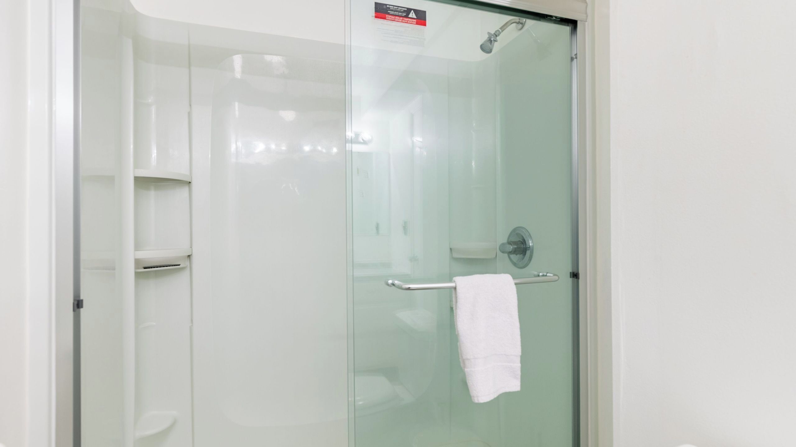 A glass-enclosed shower area with a towel rack and a toilet visible.