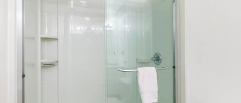 A glass-enclosed shower area with a towel rack and a toilet visible.