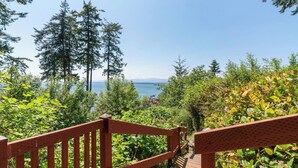 A wooden staircase leading to a scenic overlook with a view of the sea and tall trees. - Smugglers Lagoon Beach Cottage by Avantstay (Greenbank)