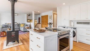 Une cuisine moderne avec des meubles blancs, un îlot central, une cuisinière et un lave-linge.
