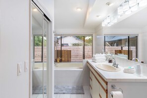 A modern bathroom with a bathtub, a sink, and a large mirror. - Oceanfront w/ Game Room, Fire Pit, Panoramic Views Angels Landing by Avantstay (Langley)