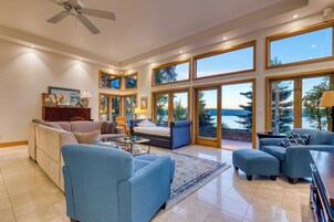 A spacious living room with a large window, a ceiling fan, and a view of the outdoors.