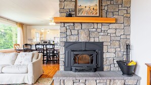 Una sala de estar acogedora con chimenea de piedra, un comedor y una cocina al fondo.