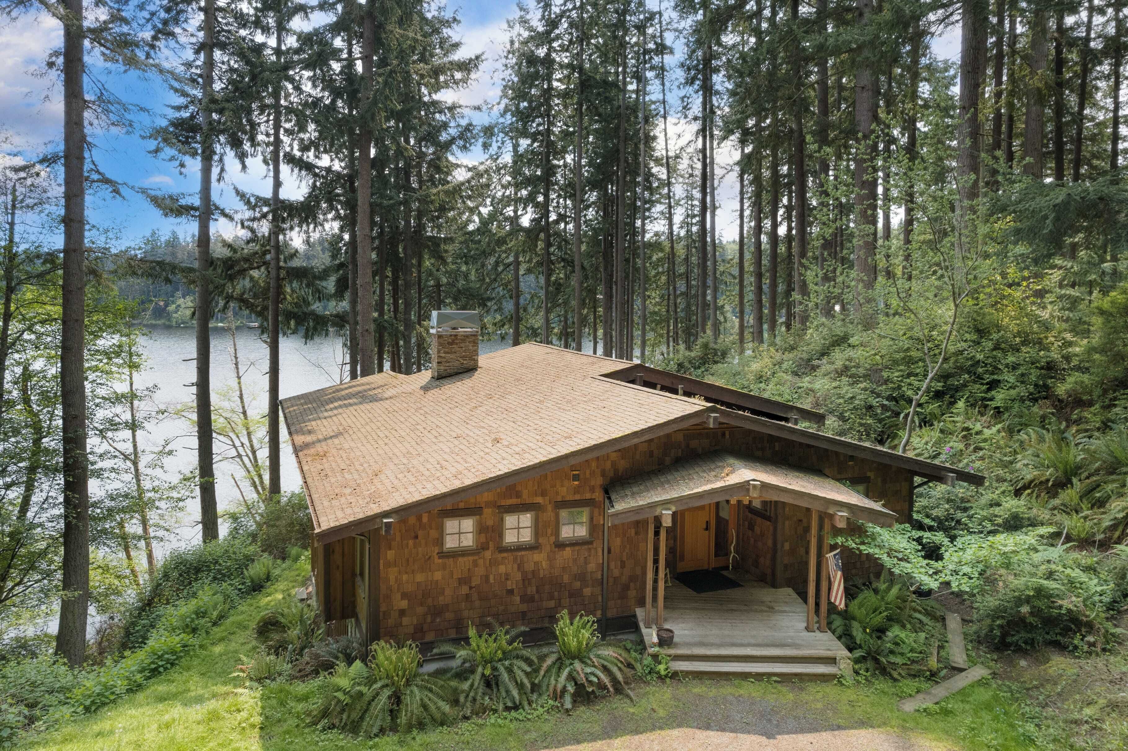A wooden cabin with a sloped roof, a chimney, and a porch with steps leading to the entrance.