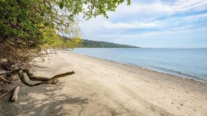 A beach with a sandy shore, trees, and a calm sea. - Barranco by Avantstay Stairway to Beach + Views (Greenbank)
