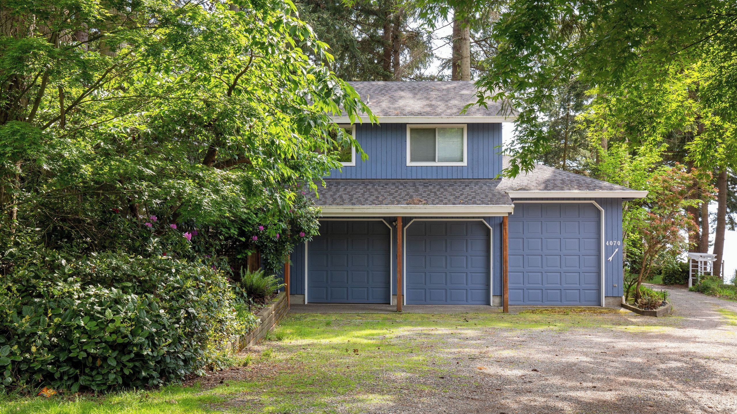 A two-story house with a blue exterior, two garage doors, and a covered driveway.