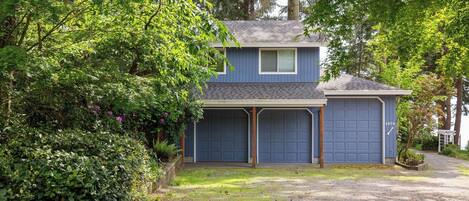 A two-story house with a blue exterior, two garage doors, and a covered driveway.