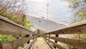 A wooden staircase leading to a beach with a rocky shoreline.