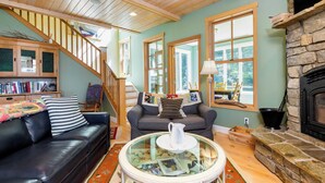 A cozy living room with a fireplace, a staircase, and a bookshelf.