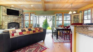A cozy living area with a fireplace, a black sofa, and a dining table with chairs.