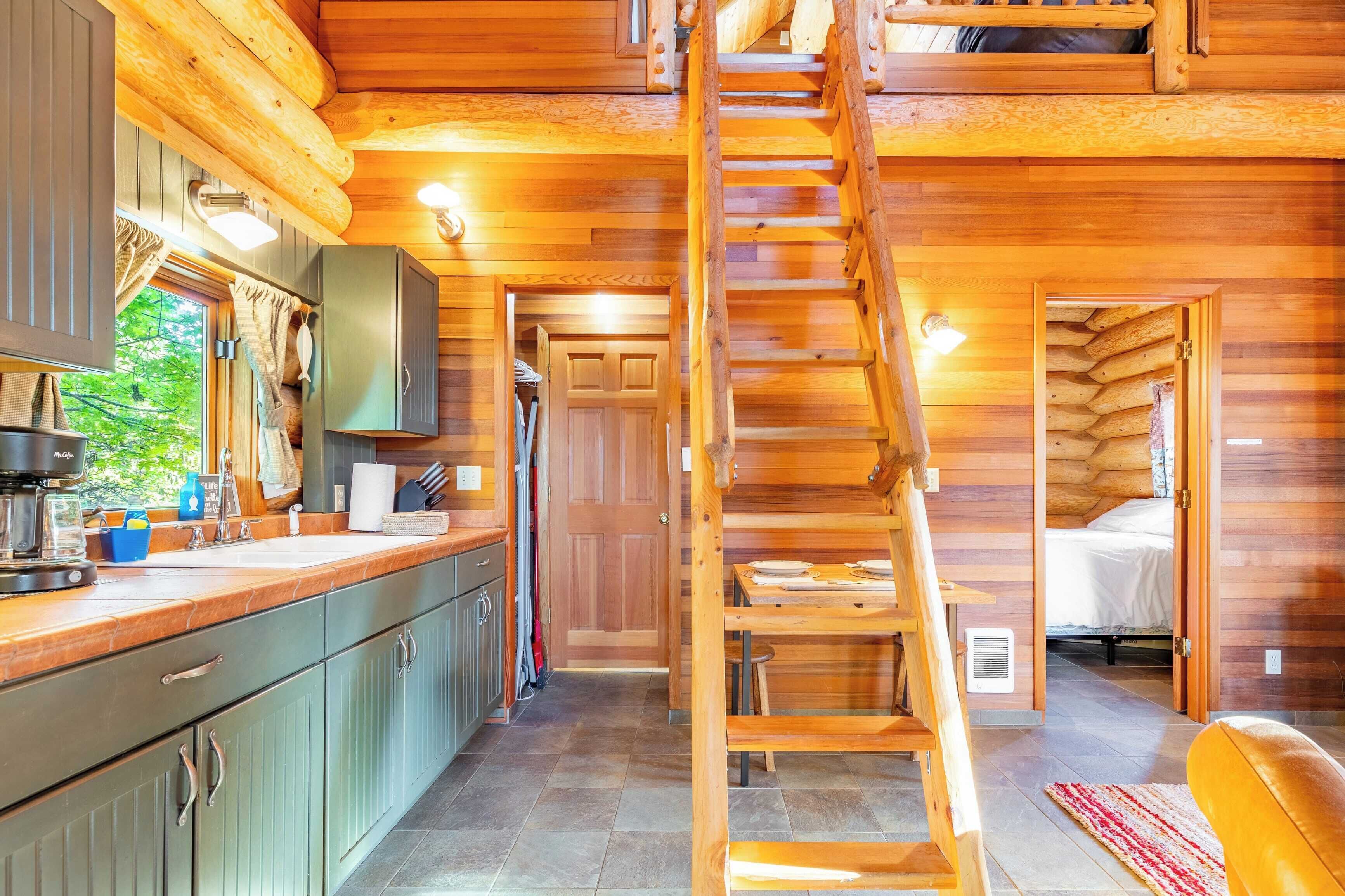 A log cabin interior with a kitchen, dining area, and a bedroom.