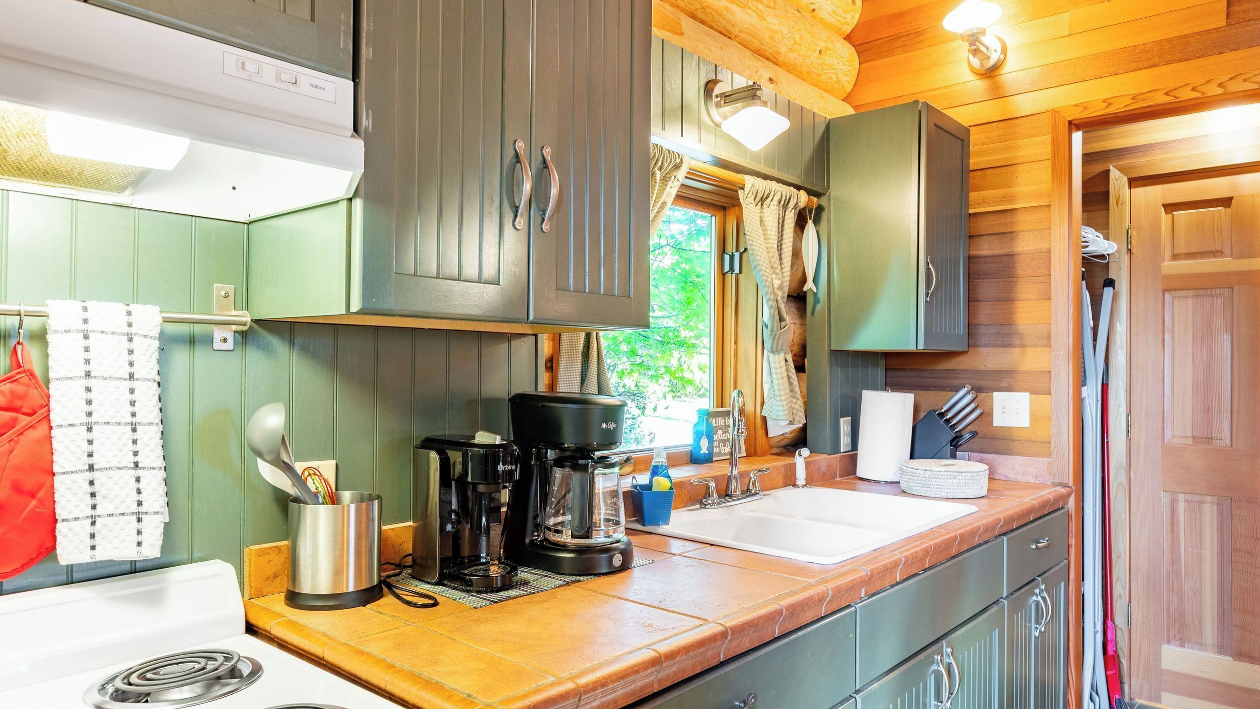 Cocina compacta con cafetera, hervidor y lavamanos.