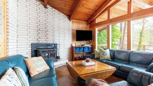 A cozy living room with a fireplace, leather sofas, a coffee table, and a TV mounted on the wall.