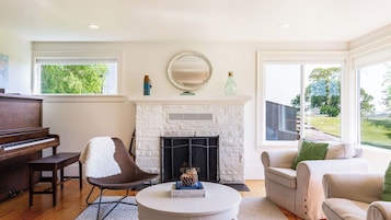 A living room with a piano, a fireplace, a round coffee table, and a couch.