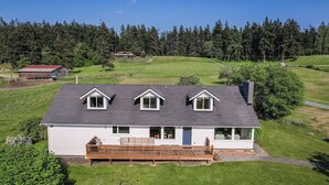 Ein eingeschossiges Haus mit überdachter Veranda, umzäunter Garten und bewaldeter Umgebung.
