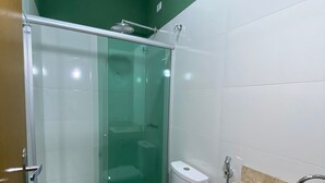 Un baño con ducha de vidrio, inodoro y lavamanos con encimera de mármol.