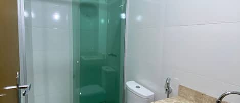 A bathroom with a glass-enclosed shower, a toilet, and a sink with a marble countertop.