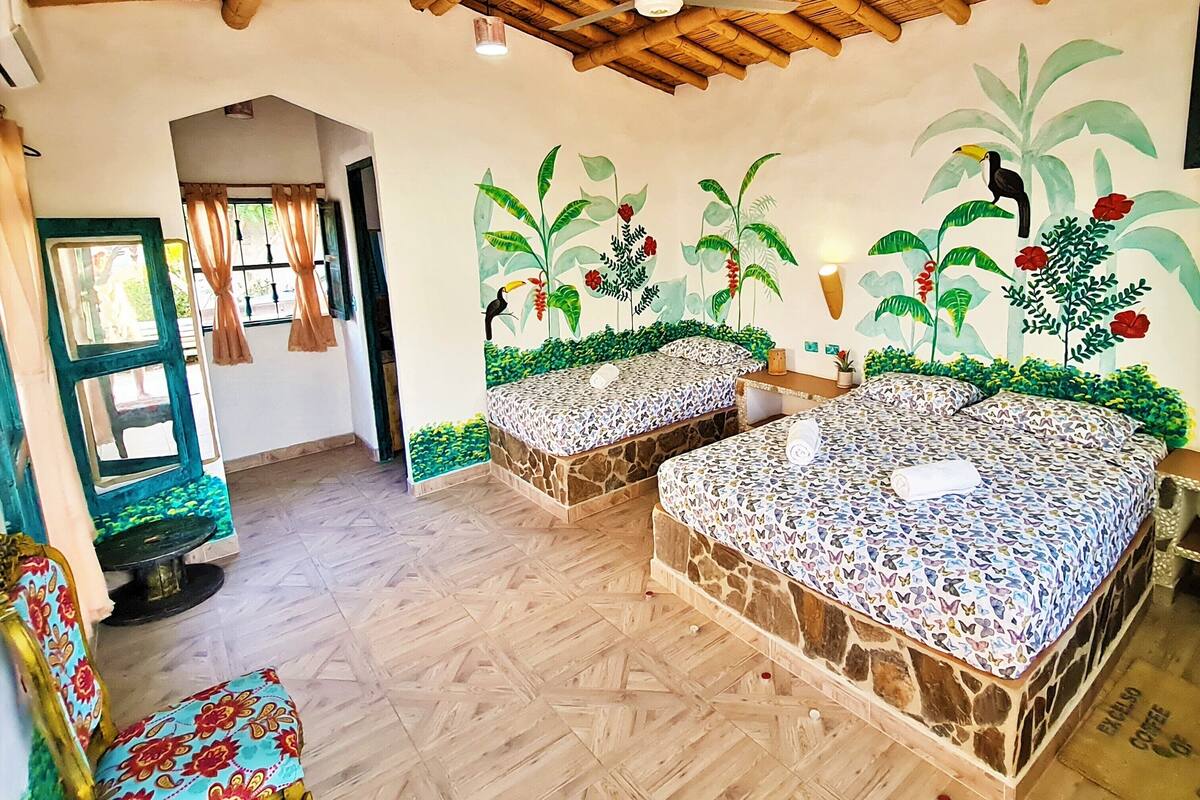 Une chambre avec deux lits, un plafond en bois et une fresque représentant des plantes tropicales.