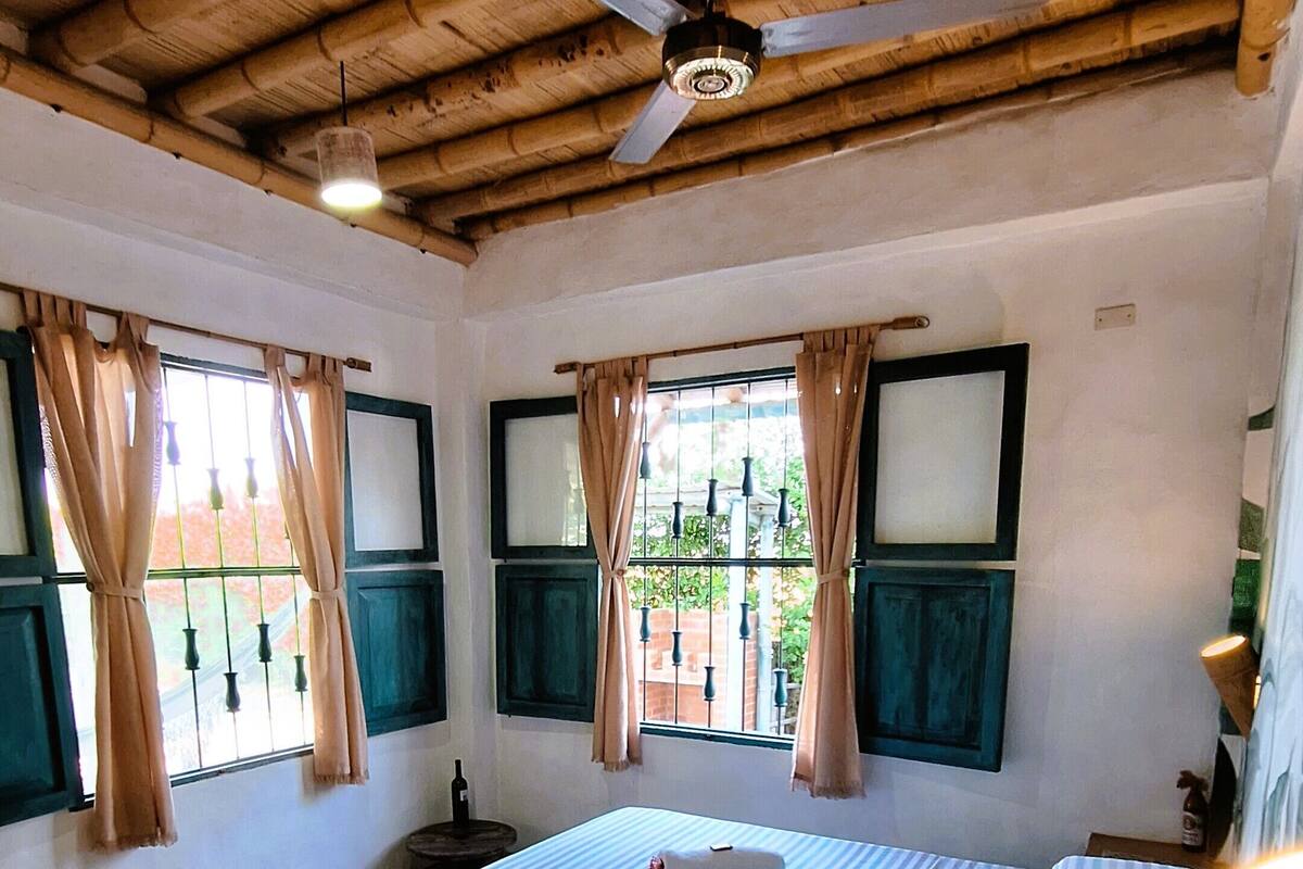 Une chambre avec un plafond en bois, un lit avec une literie à rayures et un banc en pierre.