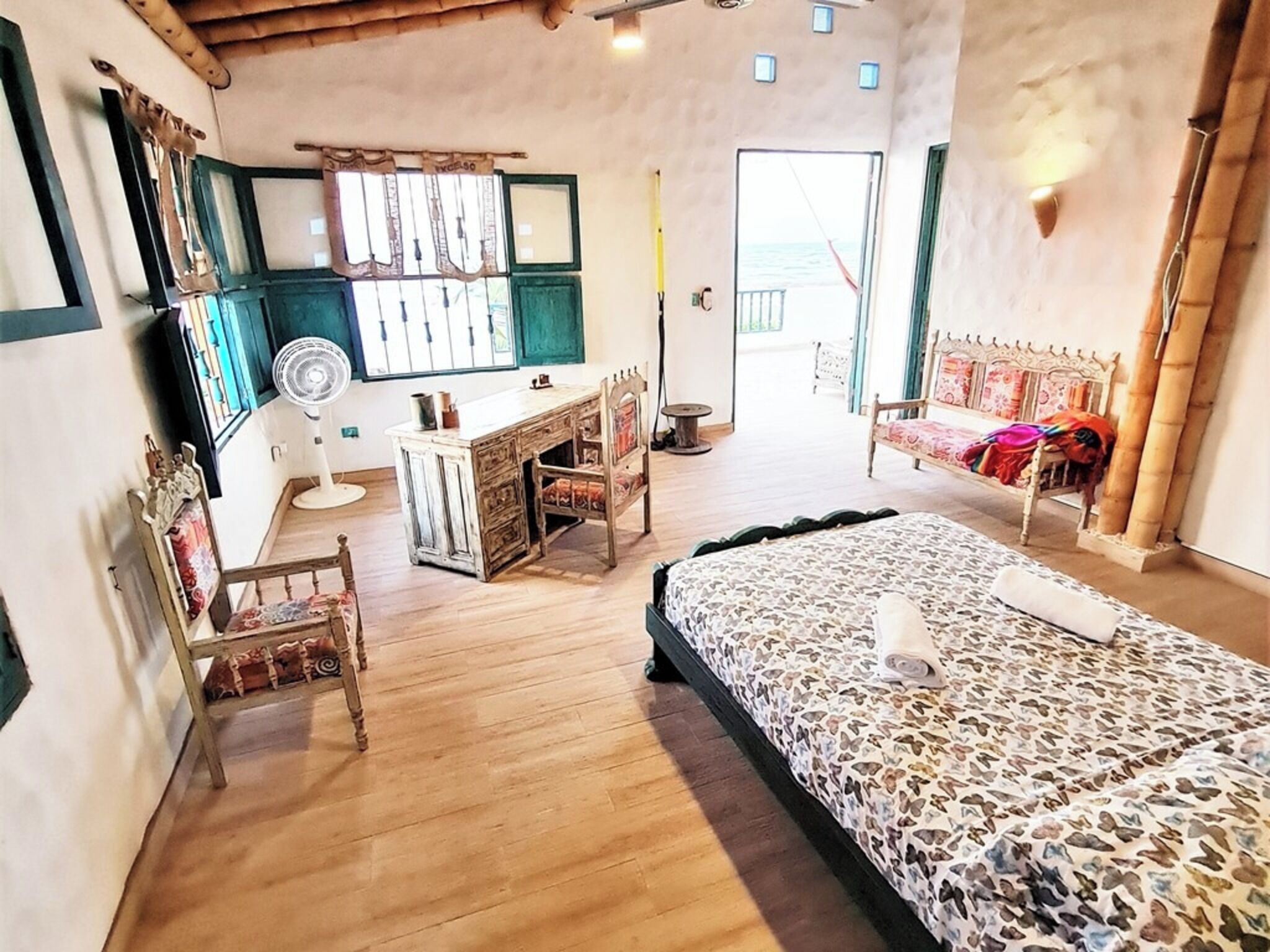 Ein Schlafzimmer mit Bett, Schreibtisch, Stühlen und Meerblick.