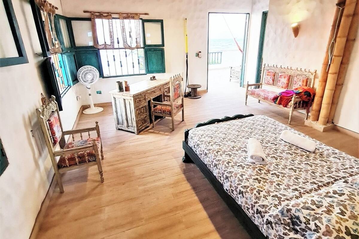 Une chambre à coucher avec un lit, un bureau, des chaises et une vue sur la mer.