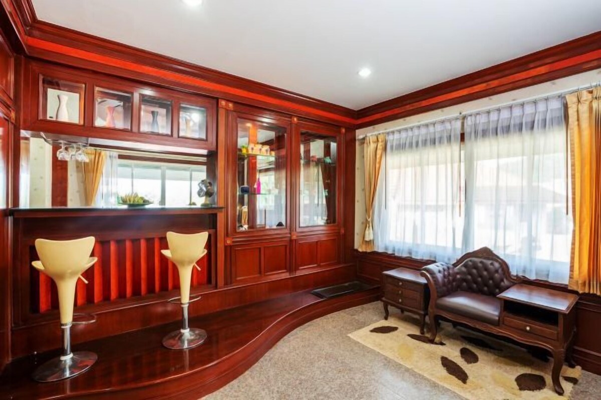 Una habitación con un banco de madera curvada, un sofá de cuero y una zona de bar con dos taburetes.
