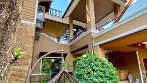 A multi-story building with balconies, a hanging chair, and a garden area. - Orchid Pool Villa Phuket (Ratsada)