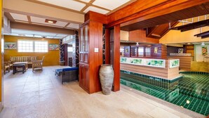 A spa area with a large tiled pool, wooden furniture, and a decorative vase. - Orchid Pool Villa Phuket (Ratsada)