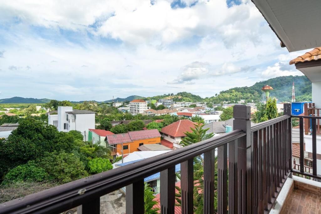 Un balcón con vistas a un pueblo, con edificios y zonas verdes.