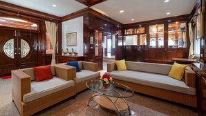 A spacious living room with wicker sofas, a glass coffee table, and wooden paneling. - Orchid Pool Villa Phuket (Ratsada)