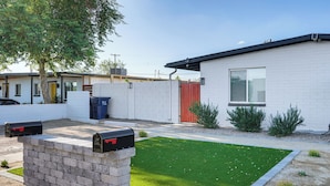 A modern house with a well-maintained lawn, a brick mailbox, and a red gate.