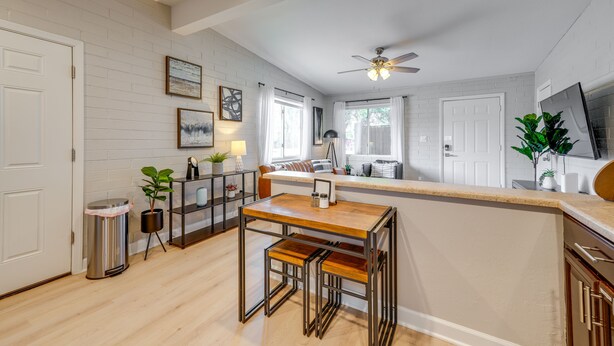 A kitchen with a wooden island, white brick walls, and a ceiling fan.