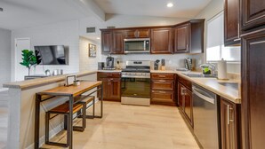 A modern kitchen with wooden cabinets, stainless steel appliances, and a built-in bench.