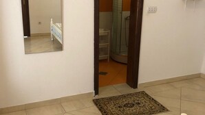 Una habitación con una cama, un espejo, una puerta que da a un baño y una alfombra pequeña en el suelo.