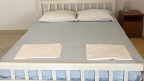 Una cama con cabecera y piecera blancos, dos almohadas y un cubrecolchón azul.
