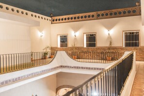 A multi-level interior with a curved balcony, decorative railings, and wall-mounted lighting.
