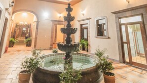 A courtyard with a central fountain, potted plants, and a tiled floor. - Hotel Boutique La Casona del Rey (San Luis Potosi)