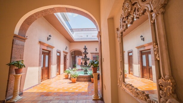 A corridor with a fountain, potted plants, and a skylight. - Hotel Boutique La Casona del Rey (San Luis Potosi)