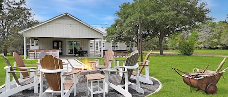 A house with a patio area featuring Adirondack chairs and a fire pit.