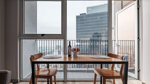 A dining area with a table and chairs, large windows, and a view of a cityscape. - Nido GDL (Guadalajara)