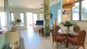A spacious living area with a dining table, chairs, and a television. - Aguas Azules Villa 1 On Corcega BEACH with POOL (Calvache)
