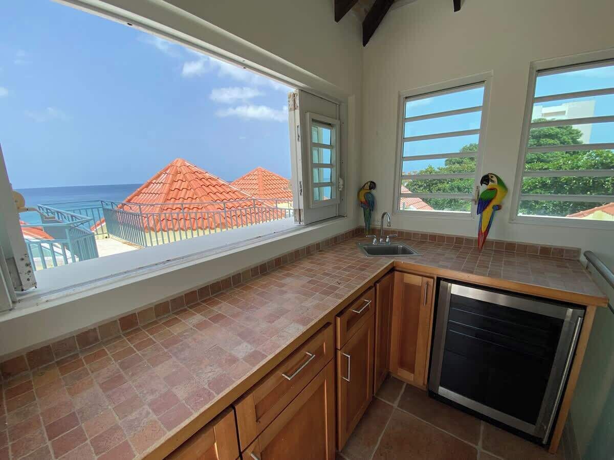 Cocina con vista al océano, un refrigerador pequeño y armarios de madera.